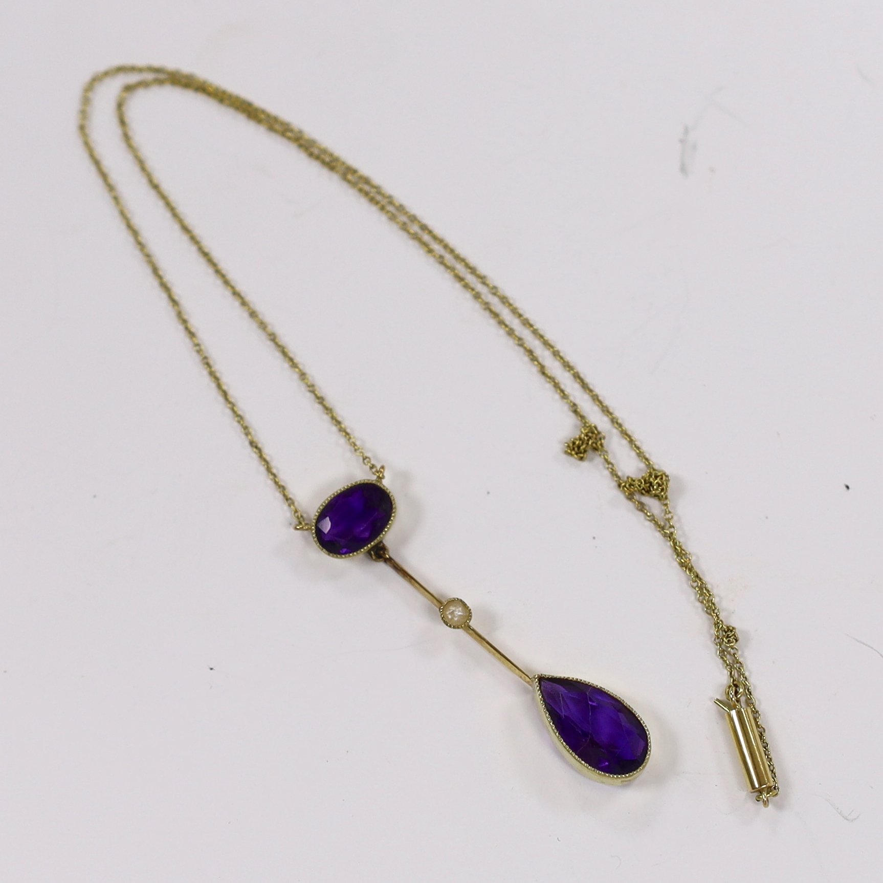An Edwardian 15ct, two stone amethyst and single stone split peal set drop pendant necklace, overall 39cm (chain knotted), gross weight 3.3 grams.